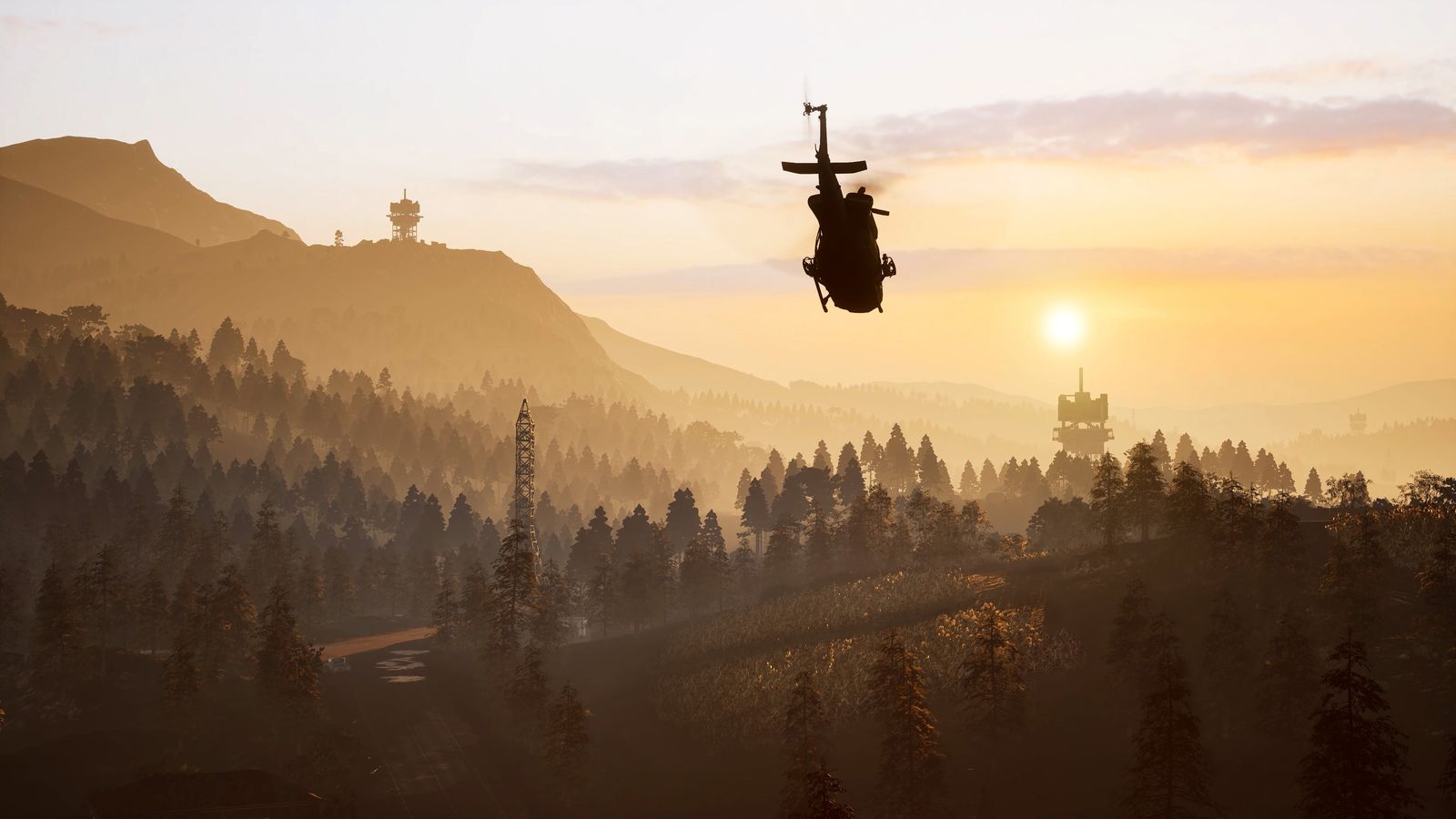 A WARDOGS helicopter silhouetted against the sunset over forested hills